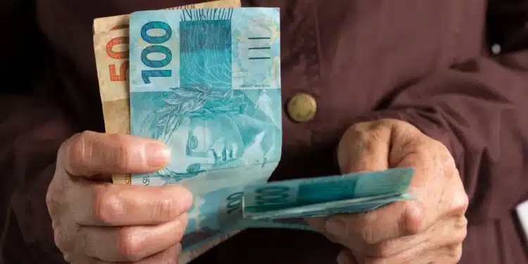 Pessoa segurando notas de 100 e 50 reais, ilustrando o auxílio do INSS sem necessidade de consulta médica.