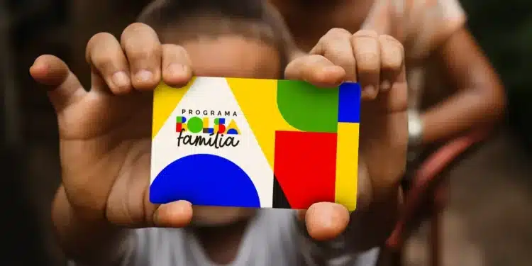 Cartão do programa Bolsa Família sendo segurado por criança, representando atualização de dados para evitar bloqueio do benefício