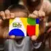 Cartão do programa Bolsa Família sendo segurado por criança, representando atualização de dados para evitar bloqueio do benefício