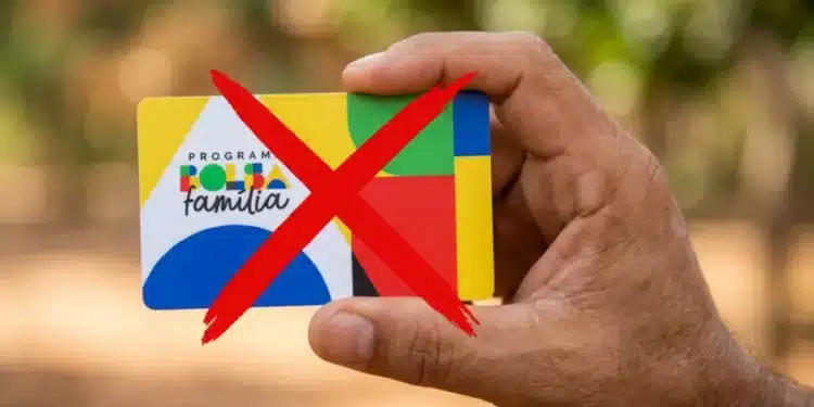 Mão segurando cartão do Bolsa Família com X vermelho, sinalizando cortes.