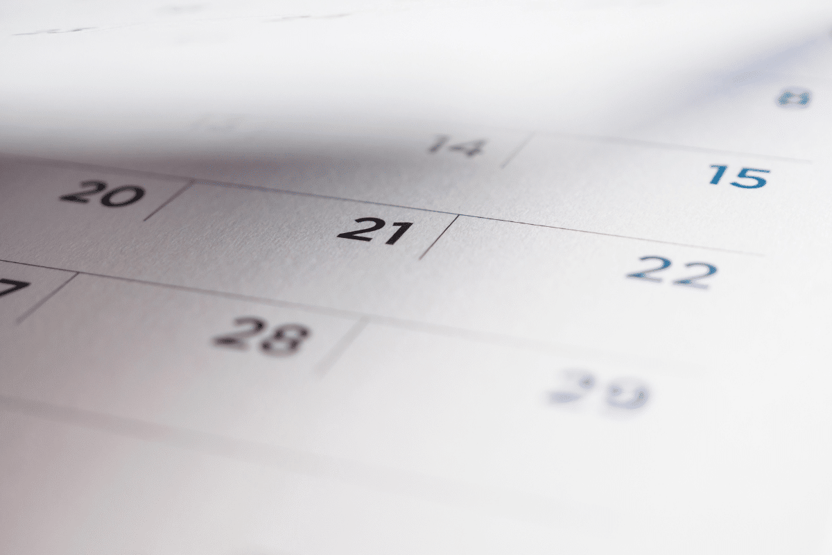 Calendário impresso em papel branco com números dos dias 14, 15, 20, 21, 22, 28 e 29 visíveis em foco seletivo
