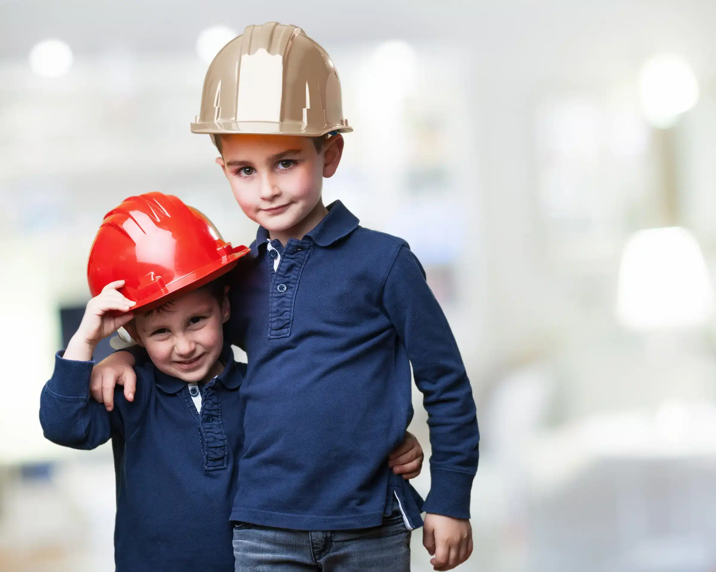 Duas crianças usando capacetes de construção simbolizando o interesse infantil pela profissão de engenheiro.