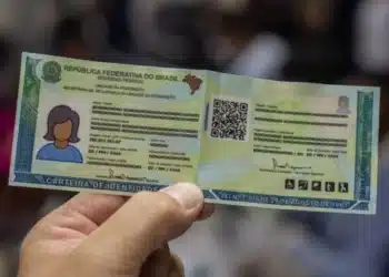 uma carteira de identidade brasileira com informações em branco, exibida por uma pessoa. O alerta do Governo estadual é sobre atualização de documentos para servidores inativos e aposentados até 30 de abril.
