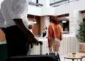 Hóspede chegando à recepção de hotel com mala para realizar check-in digital obrigatório