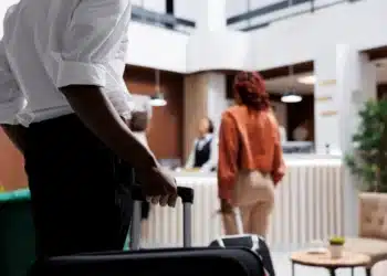 Hóspede chegando à recepção de hotel com mala para realizar check-in digital obrigatório