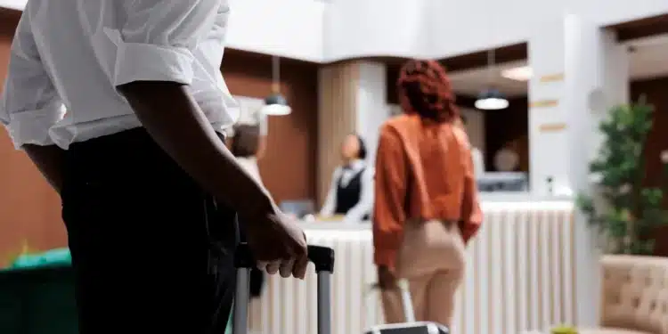 Hóspede chegando à recepção de hotel com mala para realizar check-in digital obrigatório