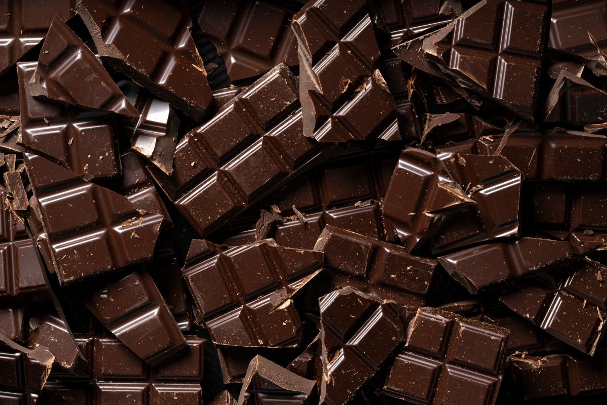 Tabletes de chocolate amargo quebrados representando o exemplo usado para explicar a grafia correta de chocolate meio amargo.