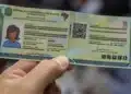 Carteira de identidade brasileira sendo segurada, representando a exigência de biometria para benefícios do INSS a partir de 2027.
