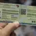 Carteira de identidade brasileira sendo segurada, representando a exigência de biometria para benefícios do INSS a partir de 2027.