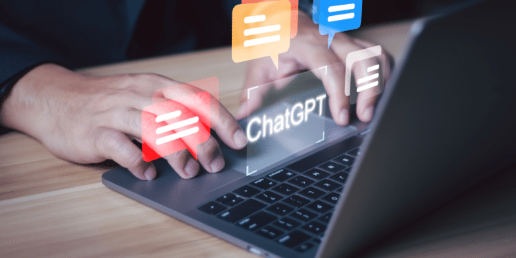 Pessoa digitando em laptop cinza com balões de conversa coloridos e texto "ChatGPT" na tela