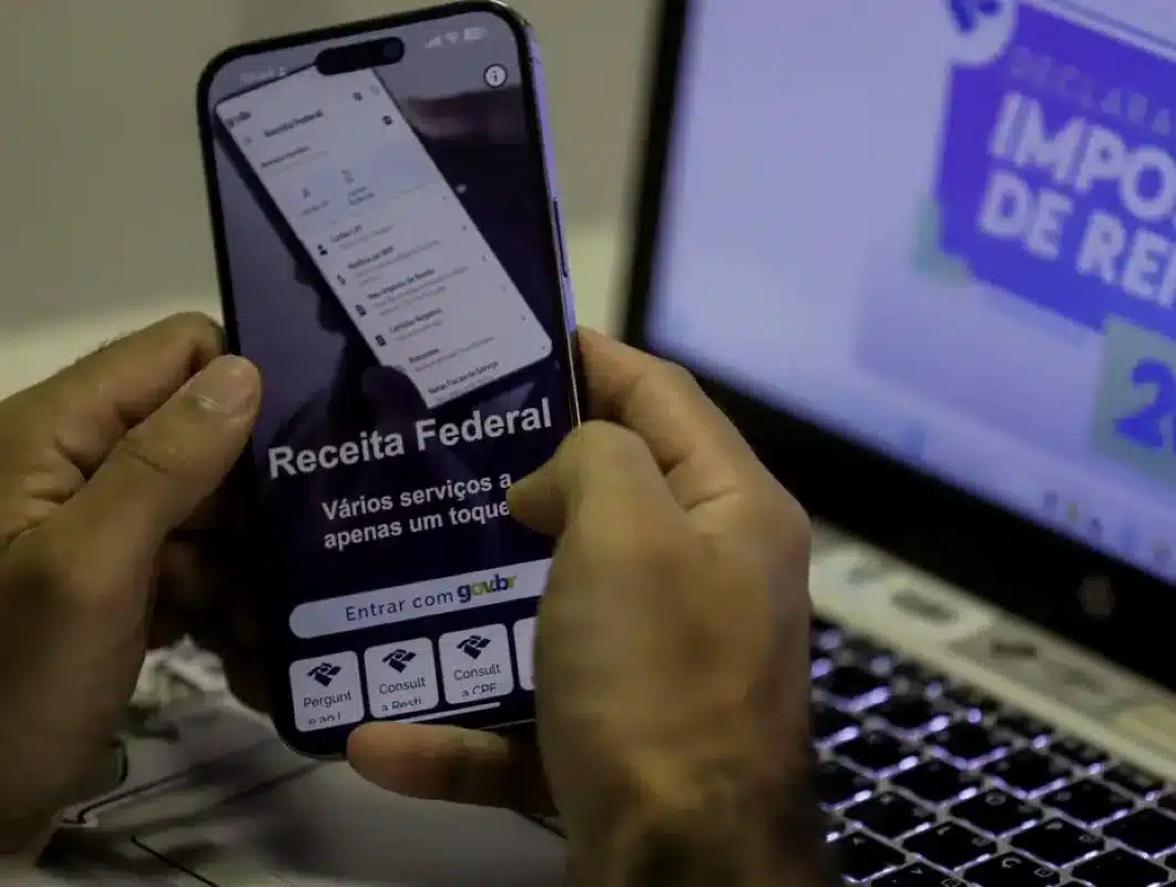 Pessoa acessando o aplicativo da Receita Federal no celular para corrigir erros na declaração do Imposto de Renda.