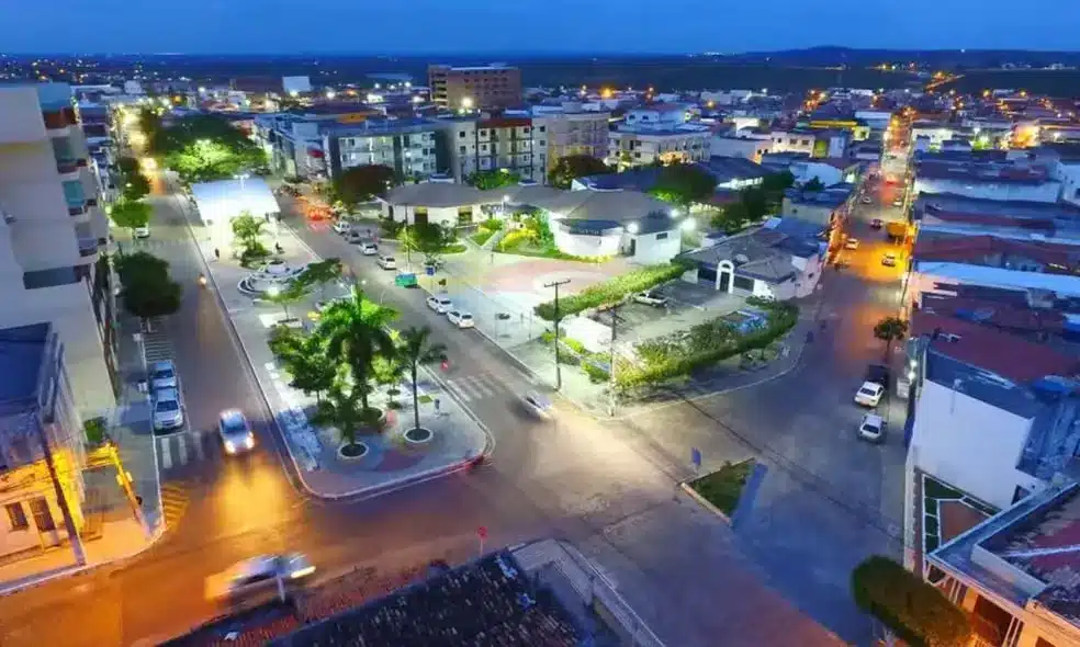 Vista aérea de Conceição do Coité à noite, mostrando ruas iluminadas e a infraestrutura urbana, contexto da inscrição para a doação de terrenos.