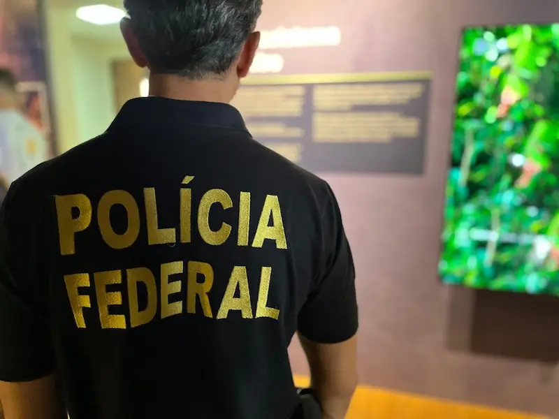 Agente da Polícia Federal com uniforme observando informações no museu, representando o avanço da minuta de decreto para nomeação de excedentes no concurso PF.