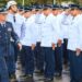 Militar da Aeronáutica com fardamento azul e medalhas passa em revista tropa de cadetes uniformizados prestando continência
