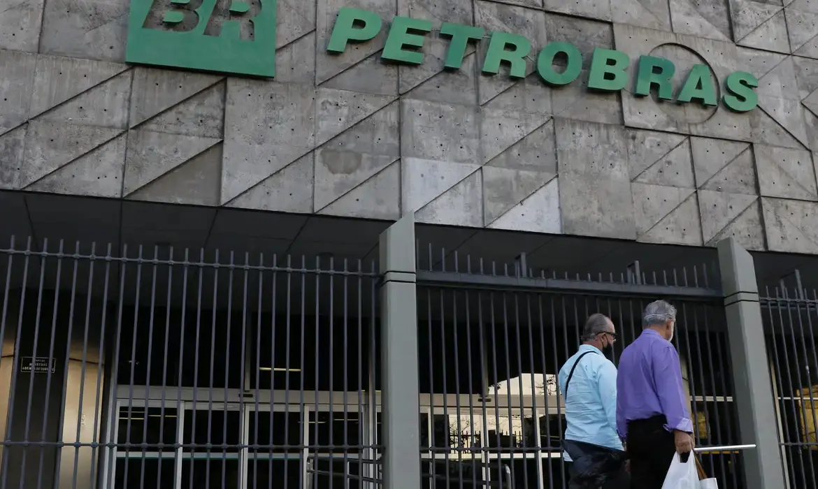 Fachada da sede da Petrobras com duas pessoas caminhando em direção à entrada.