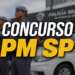 Policiais militares de SP em formação com farda azul, boinas e viatura ao fundo em frente a sede da PM