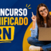 Jovem sorridente de óculos com notebook no colo e dedo levantado ao lado do texto Concurso Unificado RN