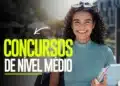 Mulher jovem de cabelos cacheados e blusa verde segura livros, sorrindo, com texto "Concursos de Nível Médio"