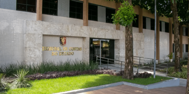 Vista externa do prédio de um Tribunal de Contas do Estado com fachada clara, árvores ao redor e placa em relevo dourado