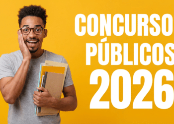 Jovem negro de óculos e cabelo crespo segura cadernos enquanto expressa surpresa com a mão no rosto, fundo amarelo