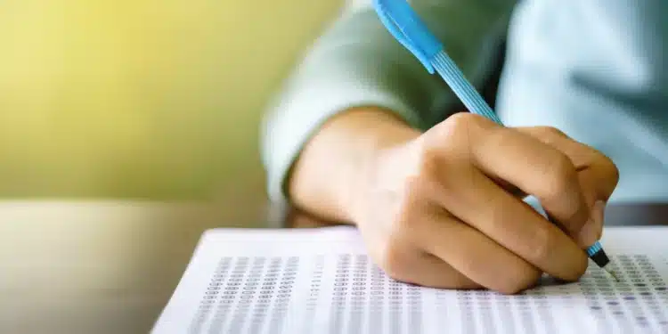 Pessoa preenchendo uma folha de respostas de concurso, simbolizando os processos seletivos para vagas no setor público, com foco nas vítimas de violência doméstica na Paraíba.