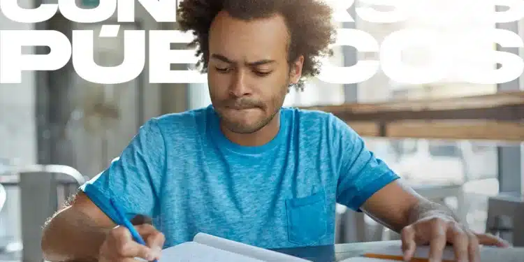 Jovem negro estudando com caneta e caderno aberto sobre mesa com texto Concursos Públicos em branco ao fundo