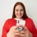 Mulher sorrindo e usando um smartphone com pop socket, criando figurinhas no WhatsApp.
