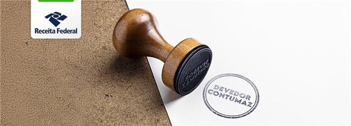 Carimbo de madeira sobre folha branca com a marca registrada "Devedor Contumaz" e logotipo da Receita Federal no canto superior esquerdo