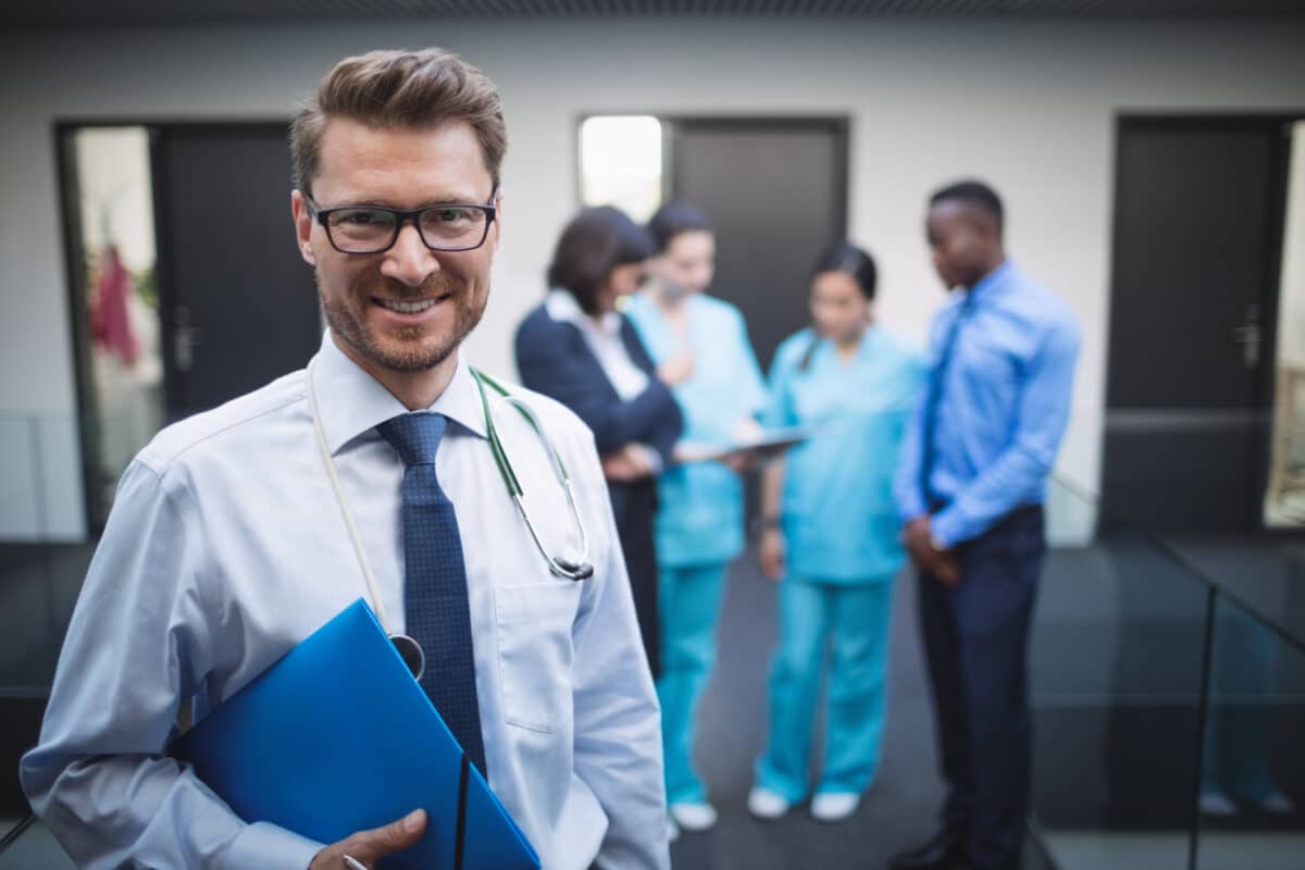 Diretor médico com alto salário CLT em hospital com equipe ao fundo