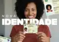 Mulher sorridente segurando a nova carteira de identidade brasileira, representando a ação de emissão gratuita do documento.