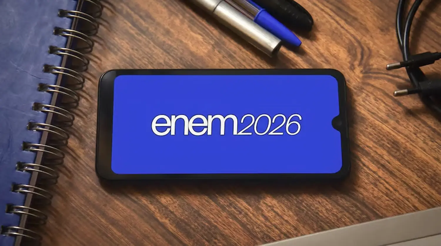 Imagem de um celular exibindo o logo do Enem 2026, rodeado por materiais de estudo, simbolizando o início dos preparativos para o exame.