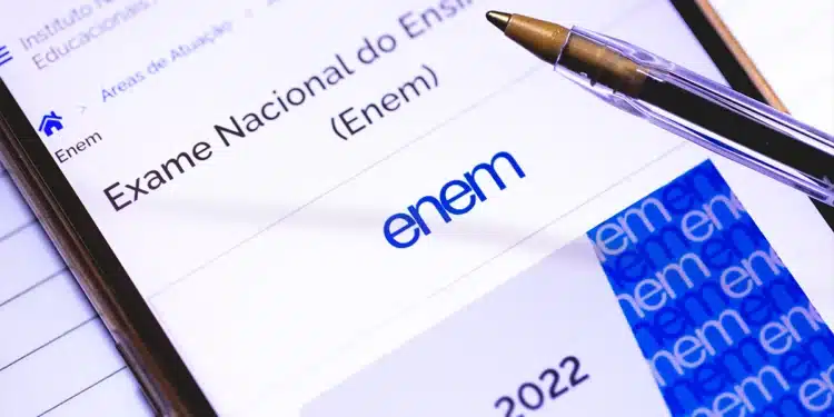 Tela de tablet mostrando site do INEP com logo ENEM 2022, caneta transparente e cartão azul ao lado
