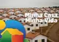 Vista aérea de casas do programa Minha Casa Minha Vida, com telhados vermelhos e a logo do programa ao lado.