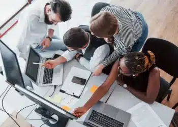 Equipe de profissionais discutindo em um escritório moderno, com foco na jornada de trabalho, representando a análise de propostas sobre jornada flexível.