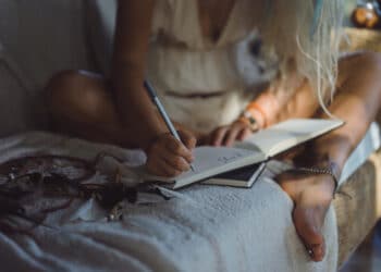 Mulher sentada escrevendo em caderno antes de dormir como técnica para acalmar a mente e dormir mais rápido