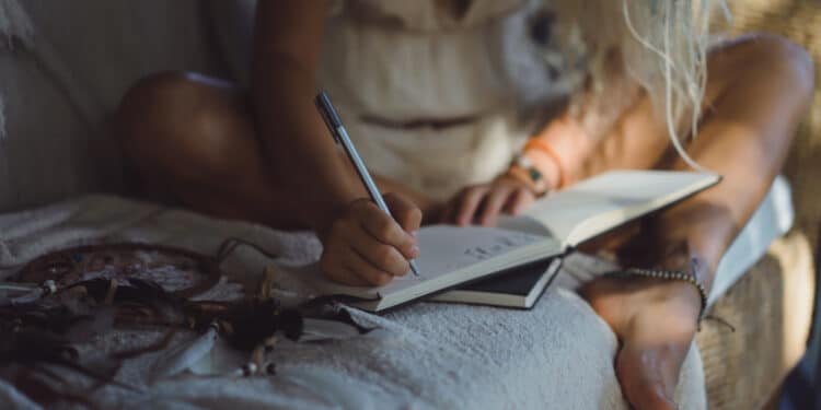 Mulher sentada escrevendo em caderno antes de dormir como técnica para acalmar a mente e dormir mais rápido