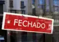 Placa de “fechado” em vitrine indicando funcionamento suspenso no feriado de 1º de maio