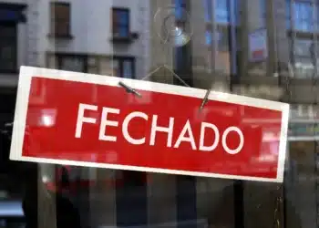 Placa de “fechado” em vitrine indicando funcionamento suspenso no feriado de 1º de maio