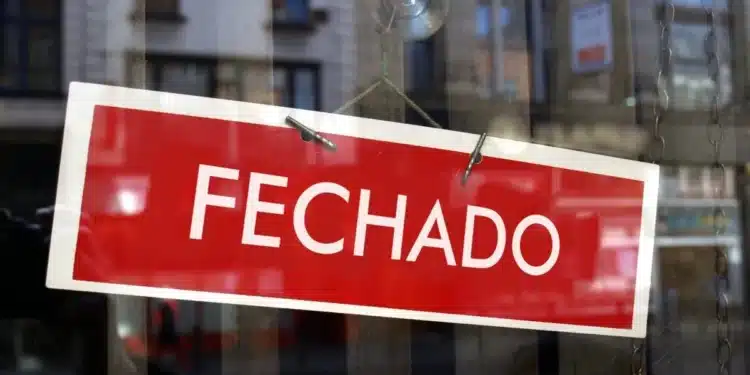 Placa de “fechado” em vitrine indicando funcionamento suspenso no feriado de 1º de maio
