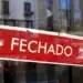Placa de “fechado” em vitrine indicando funcionamento suspenso no feriado de 1º de maio