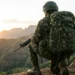 Militar do Exército Brasileiro observa paisagem montanhosa durante missão em área elevada.