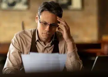 Homem preocupado revisando contas com possibilidade de pagar dívidas usando o FGTS