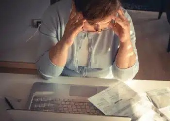 Pessoa preocupada analisando conta de luz no computador após possível golpe com empréstimo em seu nome