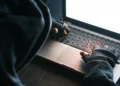 Pessoa usando notebook em ambiente escuro enquanto alerta do Gov.br destaca riscos de roubo de identidade digital.