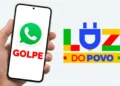 Um celular na mão de uma pessoa, com o logo do WhatsApp visível na tela, representando os golpes aplicados no WhatsApp utilizando o nome Luz do Povo.