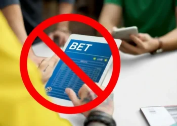 Pessoa usando tablet com site de apostas exibindo a palavra BET e símbolo de proibição indicando restrição para endividados