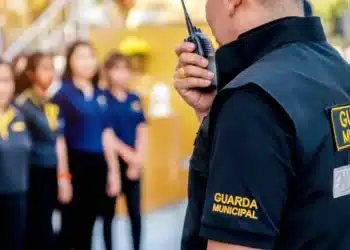 Agente da Guarda Municipal com rádio comunicador, em operação, usando uniforme com a inscrição 'GUARDA MUNICIPAL', seguindo a decisão do STF.