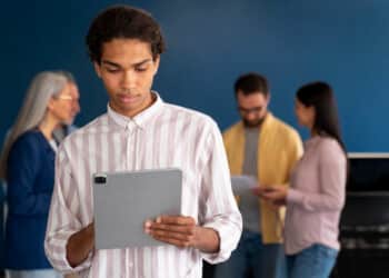 Dois profissionais analisam uma representação gráfica de cérebro artificial em um monitor, ilustrando o avanço da inteligência artificial no mercado de trabalho.