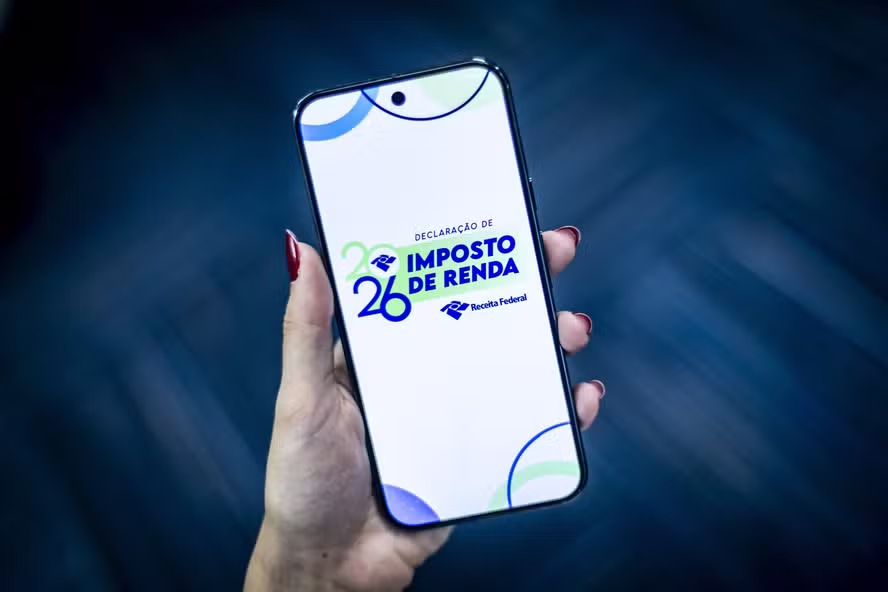 Imagem destacando a tela de um celular com a declaração de Imposto de Renda 2026, alertando sobre erros comuns na pré-preenchida devido a dados incorretos fornecidos por empresas e bancos.