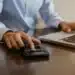 Pessoa utilizando calculadora e notebook para organizar valores do Imposto de Renda 2026 e registrar contribuições previdenciárias de dependentes.